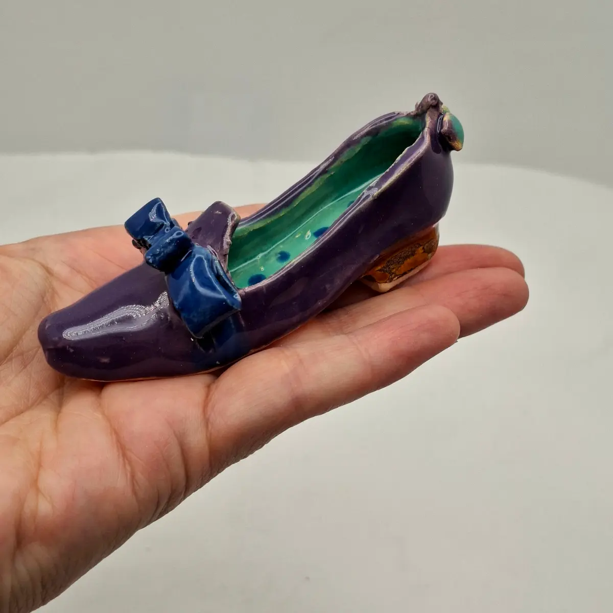 Buty ceramiczne seria sklep obuwniczy, prezent dla miłośników butów i ceramiki, prezencik ceramiczny. Fioletowe pantofelki z kokardami seria Sklep obuwniczy