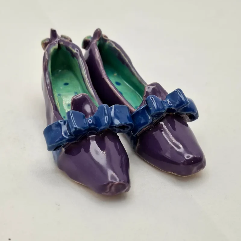 Buty ceramiczne seria sklep obuwniczy, prezent dla miłośników butów i ceramiki, prezencik ceramiczny. Fioletowe pantofelki z kokardami seria Sklep obuwniczy