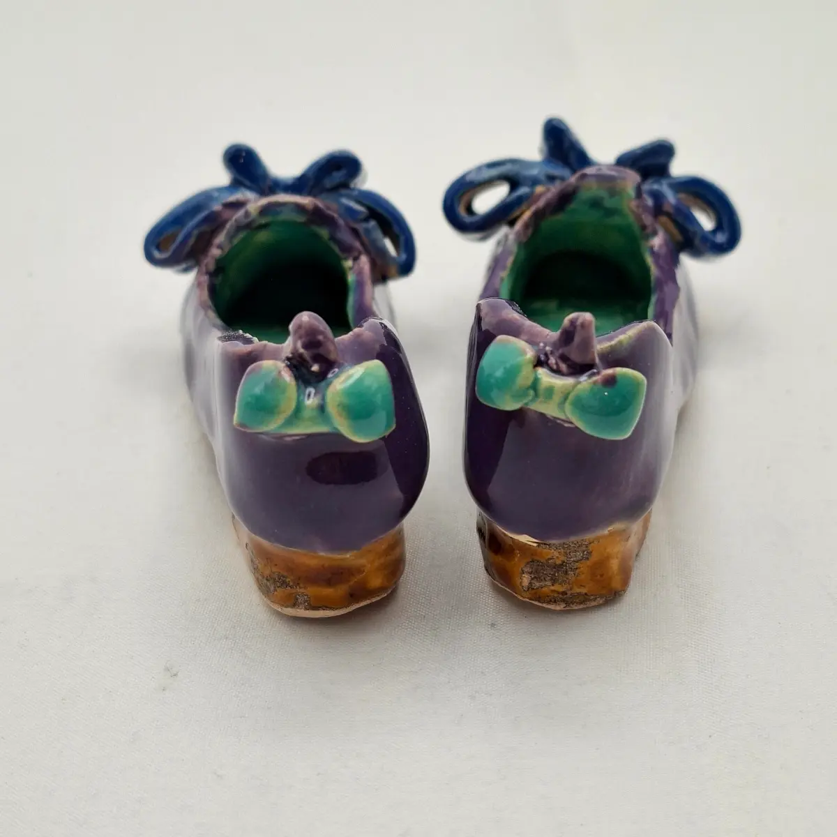 Buty ceramiczne seria sklep obuwniczy, prezent dla miłośników butów i ceramiki, prezencik ceramiczny. Fioletowe pantofelki z kokardami seria Sklep obuwniczy